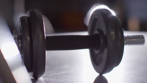 Close-Up-Studio-Fitness-Shot-Of-Hand-Picking-Up-Gym-Weight-Against-Backlight