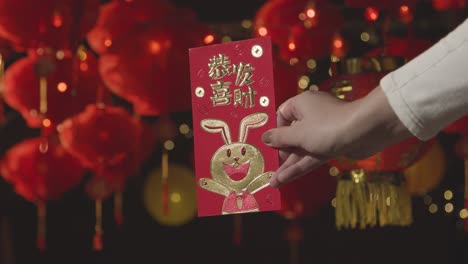 Frau-Mit-Karte,-Die-Das-Chinesische-Neujahr-2023-Feiert,-Mit-Chinesischen-Laternen,-Die-Im-Hintergrund-Aufgehängt-Sind