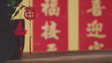 Frau-Hängt-Dekorationen,-Die-Das-Chinesische-Neujahr-Feiern,-An-Pflanzen-Zu-Hause-Mit-Banner-Im-Hintergrund-3