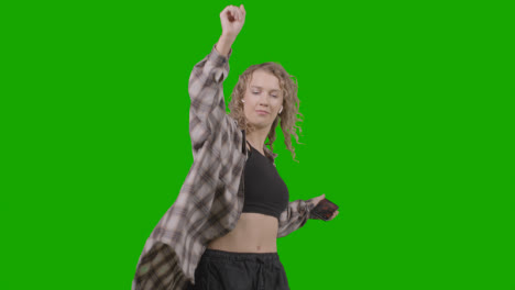Studio-Shot-Of-Young-Woman-Listening-To-Music-On-Mobile-Phone-And-Dancing-Against-Green-Screen-3