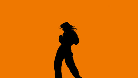 Studio-Silhouette-Of-Woman-Dancing-Against-Orange-Background