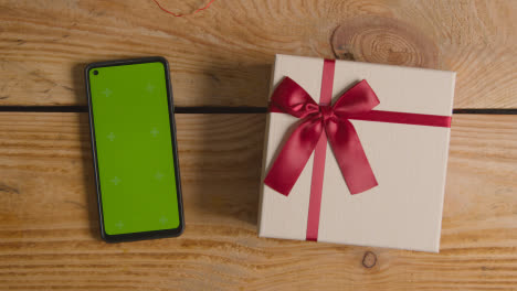 Overhead-Shot-Of-Romantic-Valentines-Present-In-Gift-Wrapped-Box-Next-To-Green-Screen-Mobile-Phone