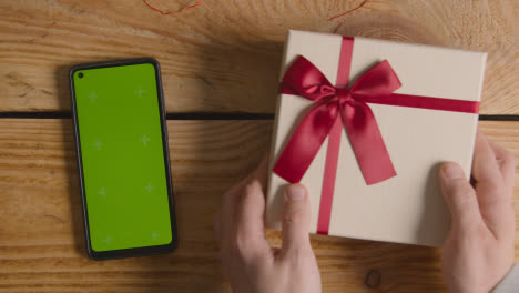 Overhead-Shot-Of-Romantic-Valentines-Present-In-Gift-Wrapped-Box-Next-To-Green-Screen-Mobile-Phone-1