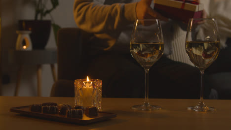 Mann-Plant-Einen-Romantischen-Abend-Zu-Hause-In-Der-Lounge-Mit-Weinschokolade-Und-Geschenk