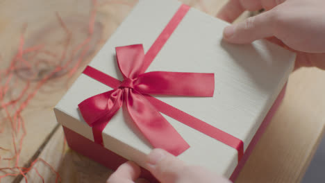 Nahaufnahme-Schuss-Von-Mann-Geschenkverpackung-Romantische-Valentinsgrüße-Vorhanden-Von-Parfüm-In-Box-Auf-Dem-Tisch