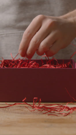 Video-Vertical-Del-Hombre-Envolviendo-Regalo-Romántico-Regalo-De-San-Valentín-De-Perfume-En-Caja-En-La-Mesa