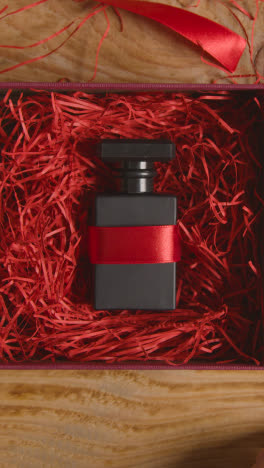 Fotografía-Cenital-De-Video-Vertical-Del-Hombre-Envolviendo-Regalos-Romántico-Regalo-De-San-Valentín-De-Perfume-En-Caja-En-La-Mesa