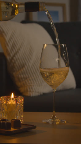 Vertical-Video-Of-Man-Planning-Romantic-Evening-At-Home-In-Lounge-With-Wine-And-Chocolates