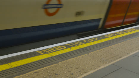 Mind-The-Gap-Warning-On-Edge-Of-Underground-Station-Platform-With-Tube-Train-Arriving