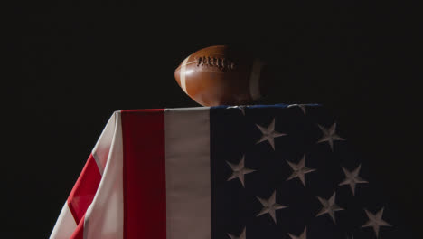 Low-Key-Lighting-Studio-Shot-Of-American-Football-On-Stars-And-Stripes-Flag-8