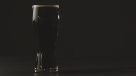 Pinta-De-Cerveza-Negra-Irlandesa-En-Vidrio-Contra-El-Fondo-Negro-Del-Estudio-Para-Celebrar-El-Día-1-De-San-Patricio