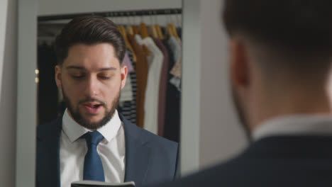 Young-Man-In-Suit-At-Home-Practising-Job-Interview-Technique-Reflected-In-Mirror-1