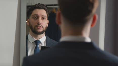 Young-Man-In-Suit-At-Home-Practising-Job-Interview-Technique-Reflected-In-Mirror-Using-Mobile-Phone