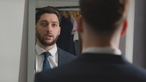 Young-Man-In-Suit-At-Home-Practising-Job-Interview-Technique-Reflected-In-Mirror-Using-Mobile-Phone-2