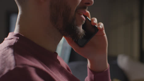 Close-Up-Of-Pleased-Young-Man-At-Home-Receiving-Phone-Call-Confirming-Job-Offer-