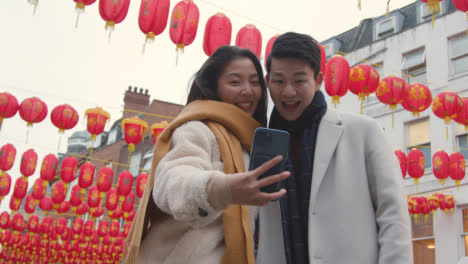 Junges-Asiatisches-Paar-Im-Urlaub-Posiert-Für-Selfie-Auf-Dem-Handy-In-Chinatown,-London,-Großbritannien