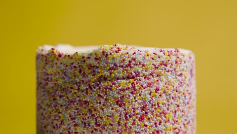 Close-Up-Studio-Shot-Of-Revolving-Birthday-Cake-Covered-With-Hundreds-And-Thousands-Decorations-7