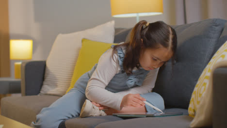 Junges-Mädchen-Sitzt-Zu-Hause-Auf-Dem-Sofa-Und-Zeichnet-Mit-Dem-Stylus-Pen-1-Auf-Einem-Digitalen-Tablet