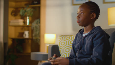 Boy-At-Home-Sitting-On-Sofa-With-Controller-Playing-Video-Game-