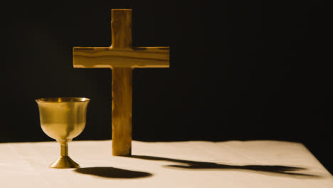 Religious-Concept-Shot-With-Wooden-Cross-And-Chalice-On-Altar-In-Pool-Of-Light-1