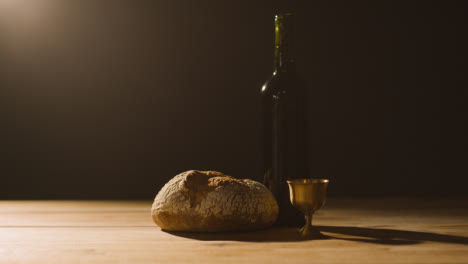 Religious-Concept-Shot-With-Chalice-Bread-And-Wine-On-Wooden-Altar-With-Pool-Of-Light