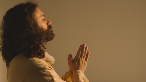 Porträt-Eines-Mannes-Mit-Langen-Haaren-Und-Bart,-Der-Die-Figur-Jesu-Christi-Darstellt,-Der-Zum-Gebet-Die-Hände-Zusammenlegt