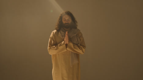 Three-Quarter-Length-Studio-Portrait-Of-Man-Wearing-Robes-And-Sandals-With-Long-Hair-And-Beard-Representing-Figure-Of-Jesus-Christ-Praying-2