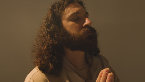 Studio-Portrait-Of-Man-Wearing-Robes-With-Long-Hair-And-Beard-Representing-Figure-Of-Jesus-Christ-Praying-2