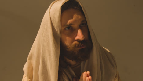 Studio-Portrait-Of-Man-Wearing-Robes-With-Long-Hair-And-Beard-Representing-Figure-Of-Jesus-Christ-Praying-8