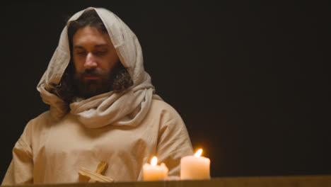 Shot-Of-Man-Wearing-Robes-With-Long-Hair-And-Beard-Representing-Figure-Of-Jesus-Christ-Holding-Wooden-Cross