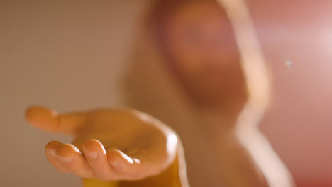 Backlit-Shot-Of-Man-With-Long-Hair-And-Beard-Representing-Figure-Of-Jesus-Christ-Extending-Hand-In-Friendship-Towards-Camera