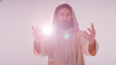 Backlit-Portrait-Of-Man-Wearing-Robes-With-Long-Hair-And-Beard-Representing-Figure-Of-Jesus-Christ-Praying-Or-Preaching
