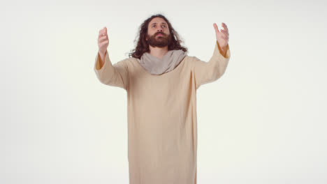 Porträt-Eines-Mannes-In-Roben-Mit-Langen-Haaren-Und-Bart,-Der-Die-Figur-Von-Jesus-Christus-Darstellt,-Der-Mit-Ausgestreckten-Armen-Betet
