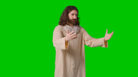 Studio-Shot-Of-Man-Wearing-Robes-With-Long-Hair-And-Beard-Representing-Figure-Of-Jesus-Christ-Preaching-On-Green-Screen