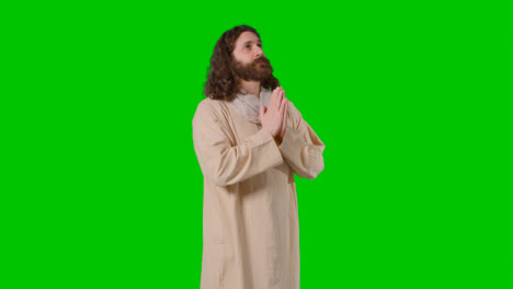 Studioaufnahme-Eines-Mannes-In-Gewändern-Mit-Langen-Haaren-Und-Bart,-Der-Die-Betende-Figur-Jesu-Christi-Auf-Grünem-Bildschirm-Darstellt-1