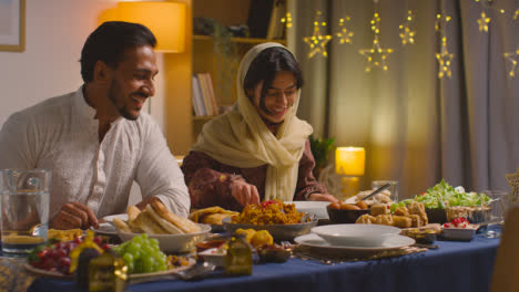 Muslim-Muslim-Family-Sitting-Around-Table-At-Home-With-Woman-Serving-Biryani-At-Meal-To-Celebrate-Eid-1