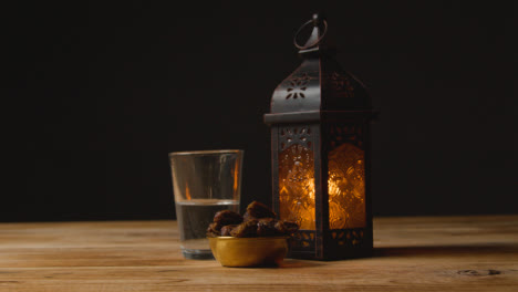 Tracking-Shot-of-Dates-Water-and-a-Lantern-On-a-Table