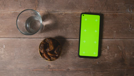 Handheld-Shot-of-Dates-and-Water-and-Green-Screen-Phone