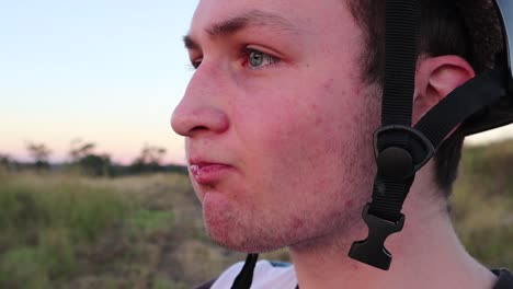 A-boy-wearing-a-helmet-stares-off-into-the-distance-whilst-drinking-from-a-water-bottle-in-slow-motion