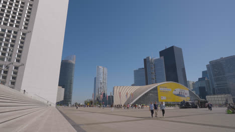 Die-Arche-De-La-Défense-Im-Geschäftsviertel-Von-Paris,-Frankreich,-Mit-Wolkenkratzern-Und-Menschen,-Die-In-Zeitlupe-Aufgenommen-Wurden