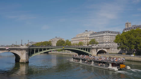 Barco-Turístico-Pasando-Por-Debajo-Del-Puente-Pont-Notre-Dame-Cruzando-El-Río-Sena-En-París,-Francia,-Con-Turistas-Y-Tráfico-1