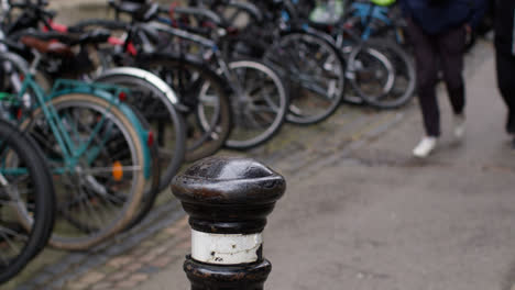 Close-Up-Of-Pedestrians-Walking-Past-Rack-Of-Bikes-Outside-College-In-City-Centre-Of-Oxford