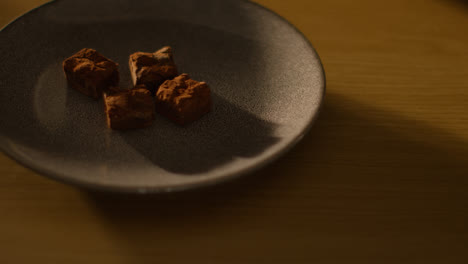 Close-Up-Of-Person-Picking-Up-And-Eating-Chocolate-Brownies-From-Plate