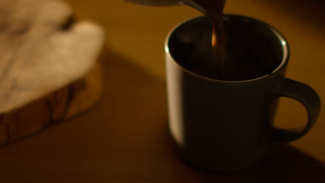 Close-Up-Of-Steaming-Hot-Chocolate-Drink-Being-Poured-Into-Cup-On-Table