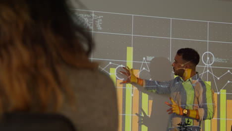 Male-Teacher-Giving-Maths-Or-Science-Lesson-In-College-Or-University-Standing-At-The-Front-Of-Class-With-Projection-Of-Graph-1