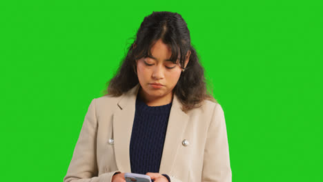 Close-Up-Studio-Shot-Of-Businesswoman-Using-Mobile-Phone-To-Message-Or-Browse-Online-Standing-Against-Green-Screen