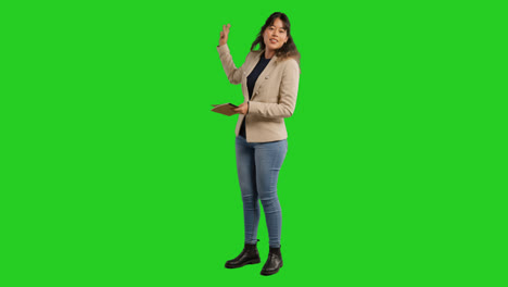 Full-Length-Studio-Portrait-Of-Female-Teacher-With-Notebook-Talking-To-Class-Standing-Against-Green-Screen-3