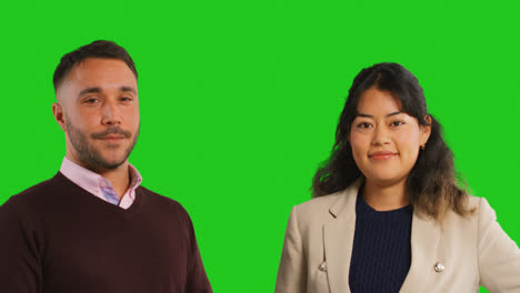 Close-Up-Studio-Portrait-Of-Male-And-Female-Teachers-Or-Businesspeople-Looking-At-Camera-Against-Green-Screen