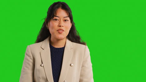 Close-Up-Studio-Portrait-Of-Female-Teacher-Or-Businesswoman-Talking-To-Class-Standing-Against-Green-Screen-Background