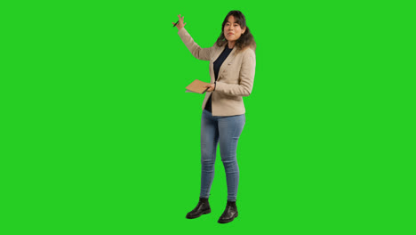 Full-Length-Studio-Portrait-Of-Female-Teacher-With-Notebook-Talking-To-Class-Standing-Against-Green-Screen-2